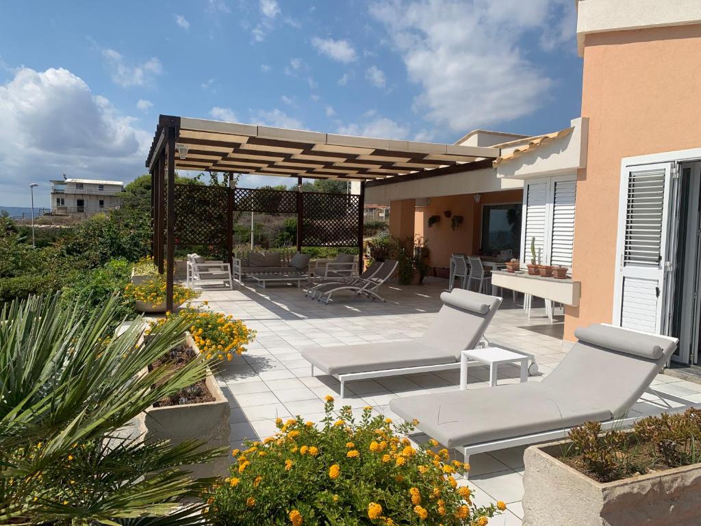 une terrasse avec 2 chaises longues et une pergola dans l'établissement Villa Luce, à Syracuse