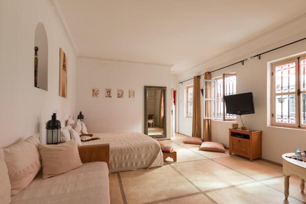 une chambre avec un lit, un canapé et une télévision dans l'établissement Riad Alegria, à Marrakech