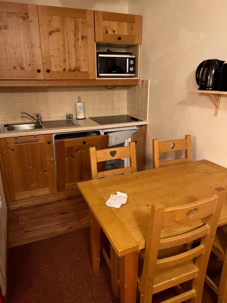 une cuisine avec une table en bois et une table et des chaises dans l'établissement Les alpages location appartement 108, à Lanslebourg-Mont-Cenis