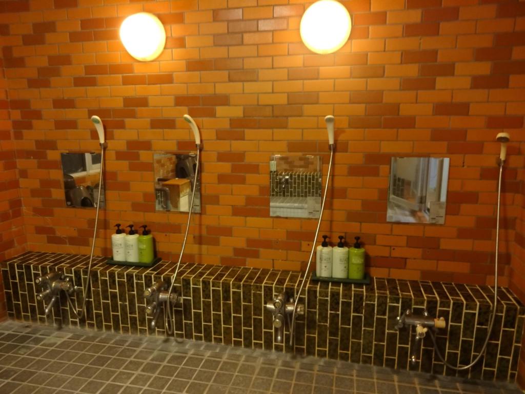 - une salle de bains avec 3 urinoirs et des bouteilles sur un mur dans l'établissement Resort Inn Seikan, à Hakuba