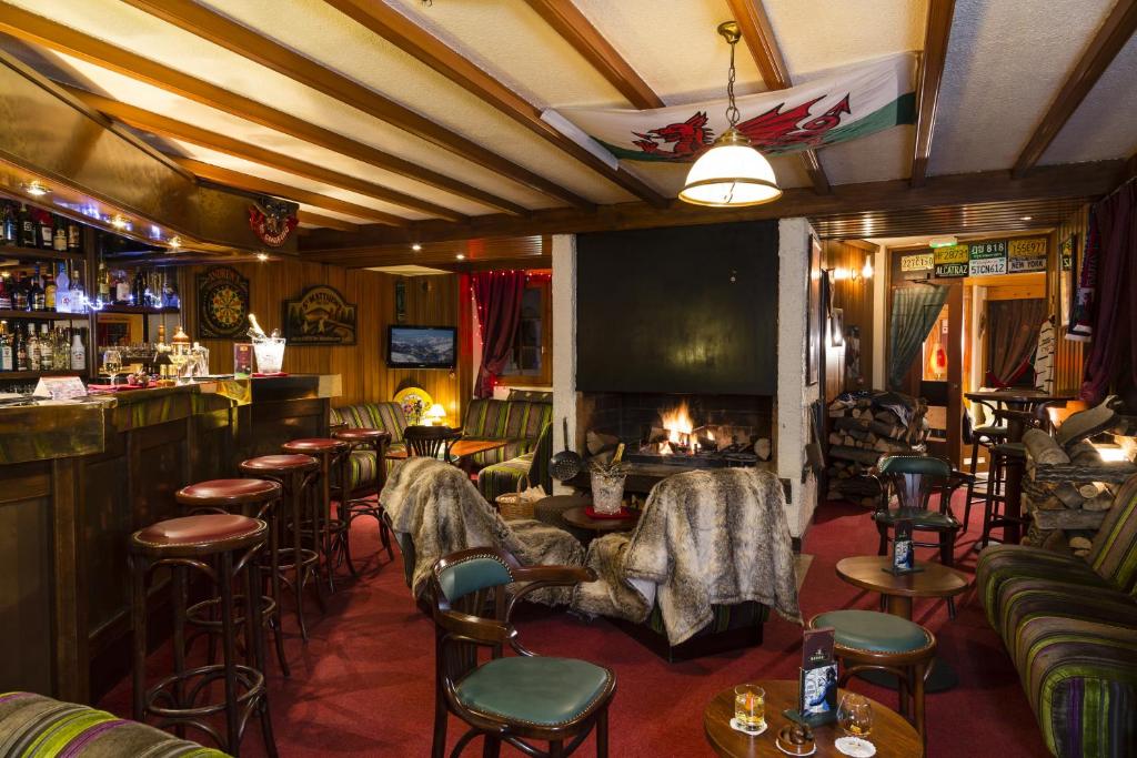 - un bar avec des chaises et une cheminée dans la pièce dans l'établissement Hôtel du Bourg, à Valmorel
