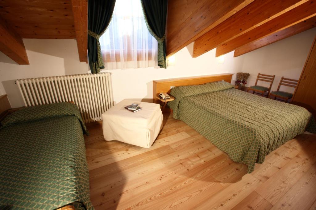 - une chambre avec 2 lits verts et du parquet dans l'établissement Garni Lago Nembia, à San Lorenzo in Banale