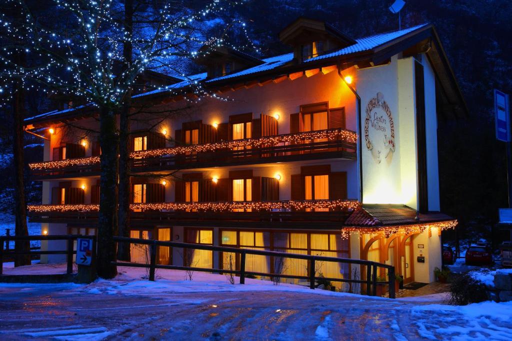 une maison avec des lumières de Noël dans la neige dans l'établissement Garni Lago Nembia, à San Lorenzo in Banale
