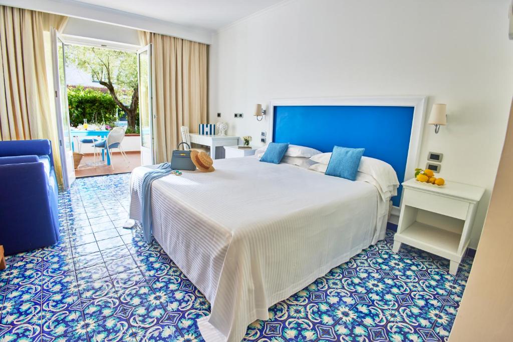 une chambre avec un grand lit avec une tête de lit bleue dans l'établissement Oleandri Resort Paestum, à Paestum