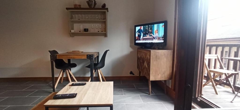 un salon avec une télévision, une table et des chaises dans l'établissement LUMINEUX 30 m avec BALCON- CENTRE VILLAGE, au Monêtier-les-Bains
