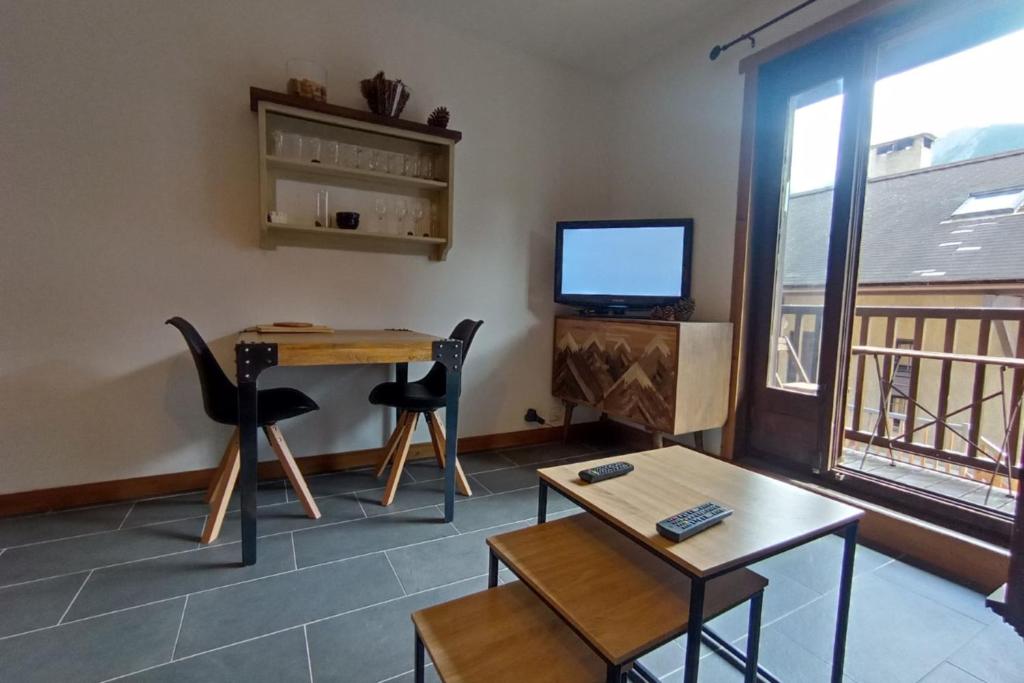 un salon avec une table et une télévision dans l'établissement LUMINEUX 30 m avec BALCON- CENTRE VILLAGE, au Monêtier-les-Bains