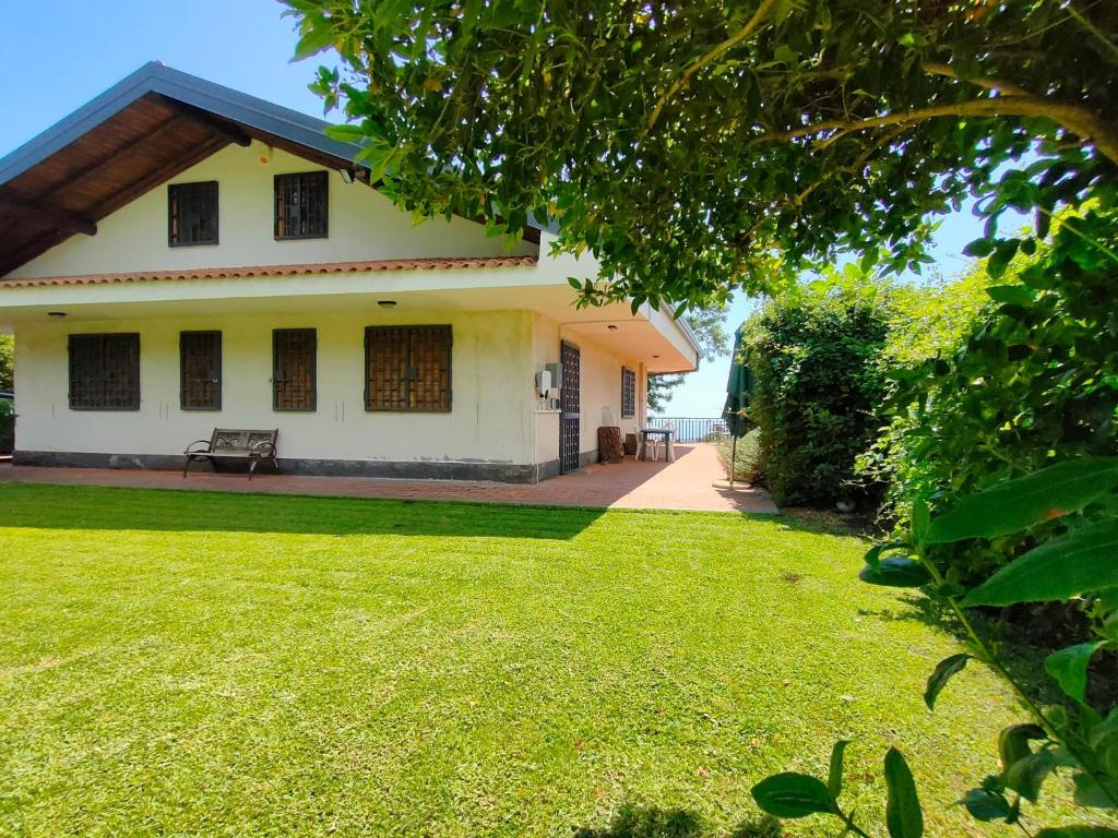 une maison avec une pelouse verte devant dans l'établissement Villa Mimosa, à Zafferana Etnea