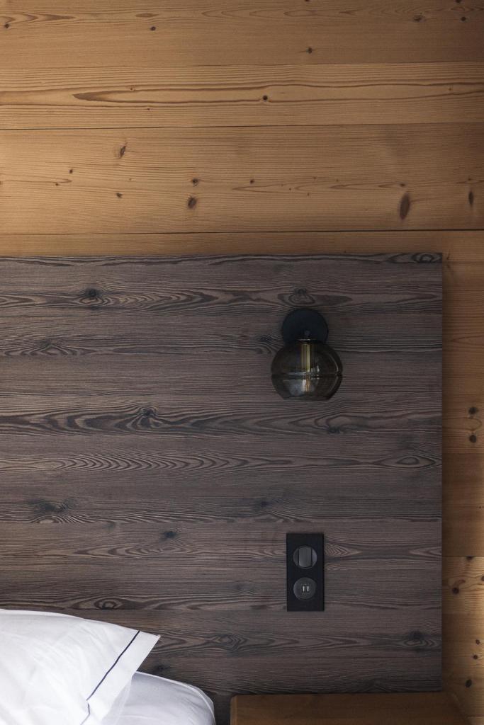 une chambre avec un mur en bois avec une lumière dessus dans l'établissement Les Cèdres - Hôtel - Restaurants - Spa, à Saint-Sorlin-dʼArves