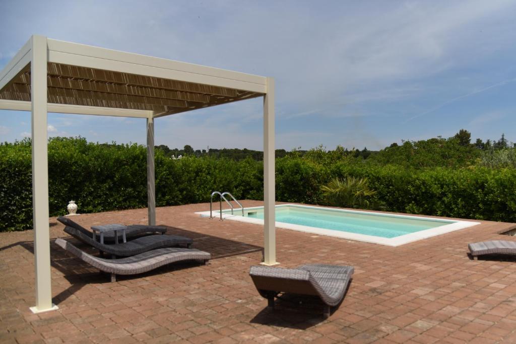 une piscine avec des chaises longues et un pavillon à côté d'une piscine dans l'établissement Trullo delle Querce Suite Private Pool, à Martina Franca