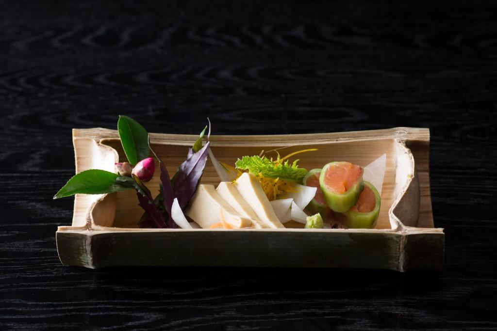un récipient rempli de légumes et de fruits sur une table dans l'établissement Chikurakutei, à Minami Aso