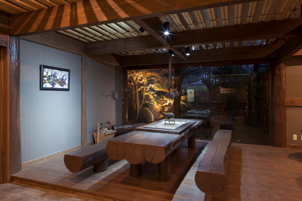 une salle à manger avec une table et des bancs en bois dans l'établissement Chikurakutei, à Minami Aso
