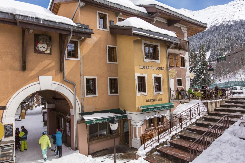 Un bâtiment avec des personnes debout à l'extérieur dans la neige dans l'établissement Hôtel du Bourg, à Valmorel