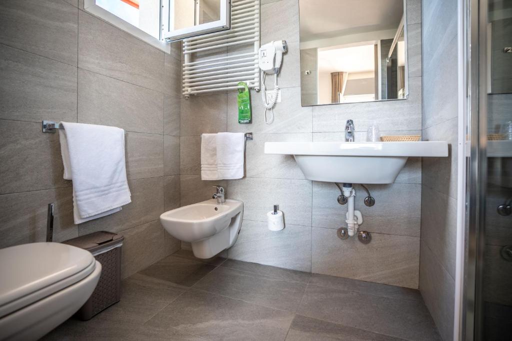 une salle de bain avec un lavabo et des toilettes dans l'établissement Hotel Loreley, à Lido di Jesolo 82 autres photos