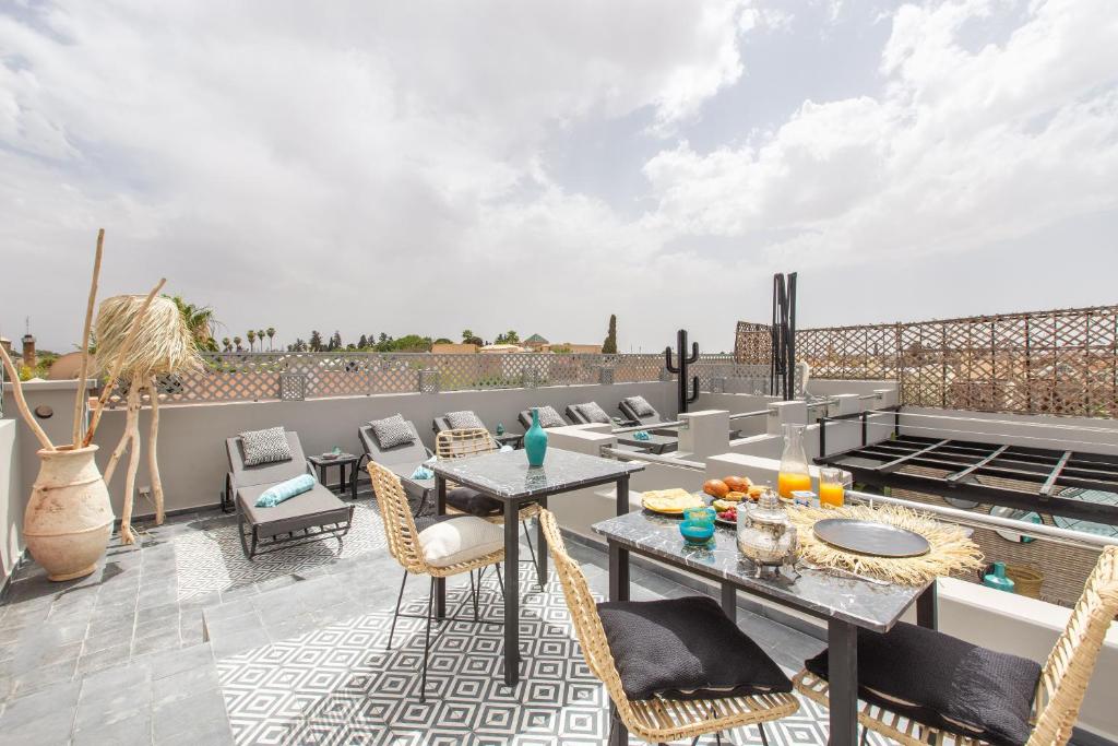 un patio avec une table et des chaises sur un toit dans l'établissement Riad Princesse Des Sables- Jaccuzzi& SPA-Breakfast, à Marrakech
