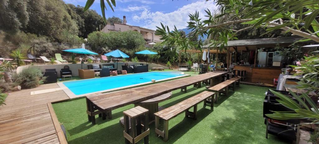 une piscine avec bancs et parasols dans une cour dans l'établissement Gites San Austinu, à Petreto-Bicchisano
