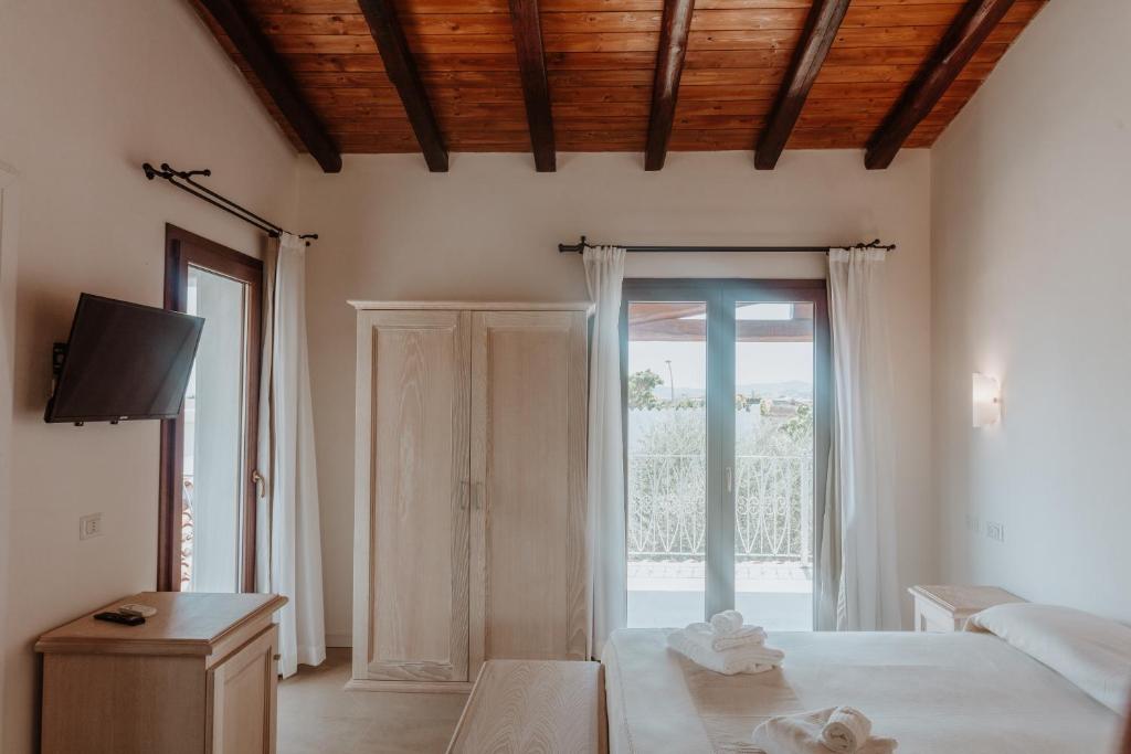 une chambre avec un lit et une porte coulissante en verre dans l'établissement Resort Fior di Sardegna, à Posada