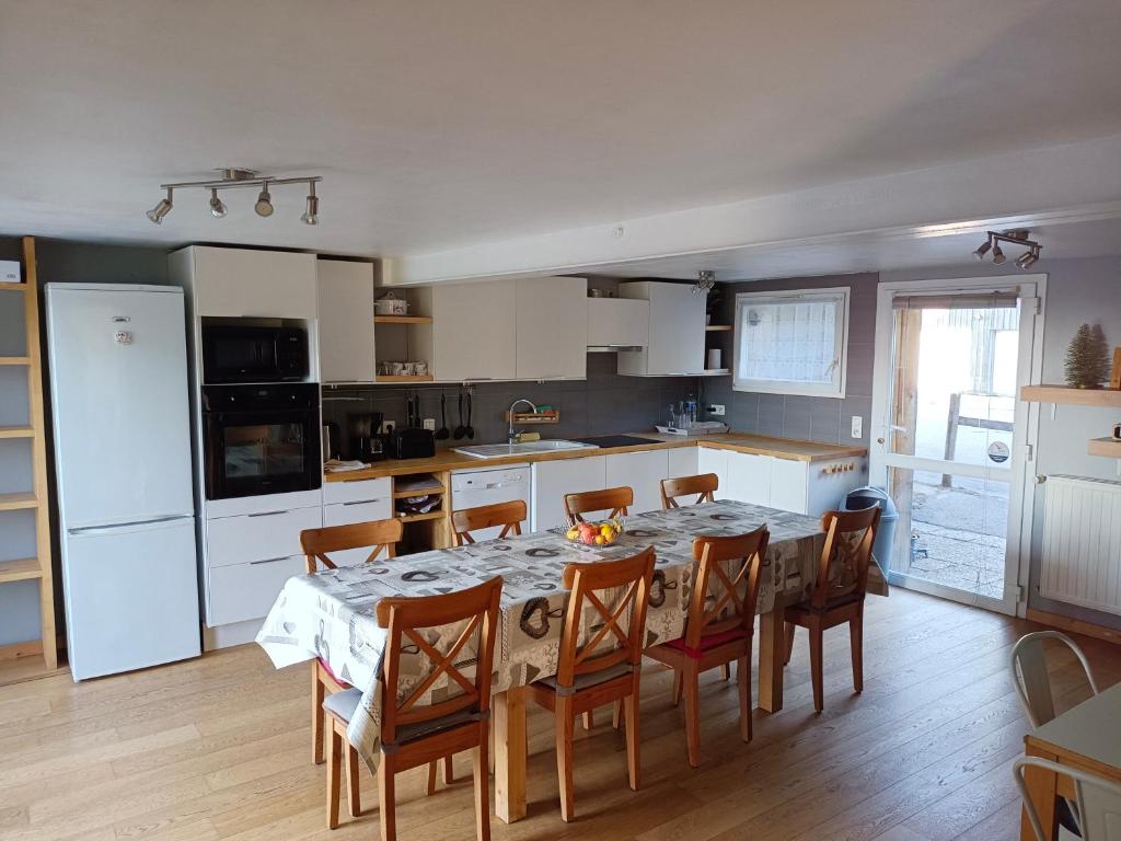 une cuisine avec une table et des chaises dans une cuisine dans l'établissement Les Jonquilles: gîte 8/10 pers. avec vue imprenable!, à Gérardmer