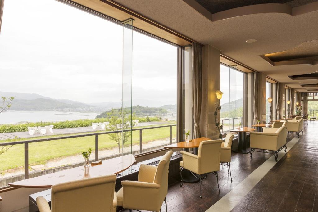 un restaurant avec des tables et des chaises et de grandes fenêtres dans l'établissement Wano Resort Hazu, à Gamagori 37 autres photos