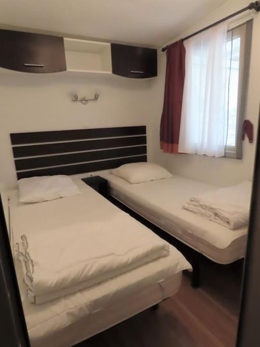 deux lits dans une petite pièce avec une fenêtre dans l'établissement Mobile home 6-pers Camping Leï Suves-Côtes d'Azur-including airco, à Roquebrune-sur Argens