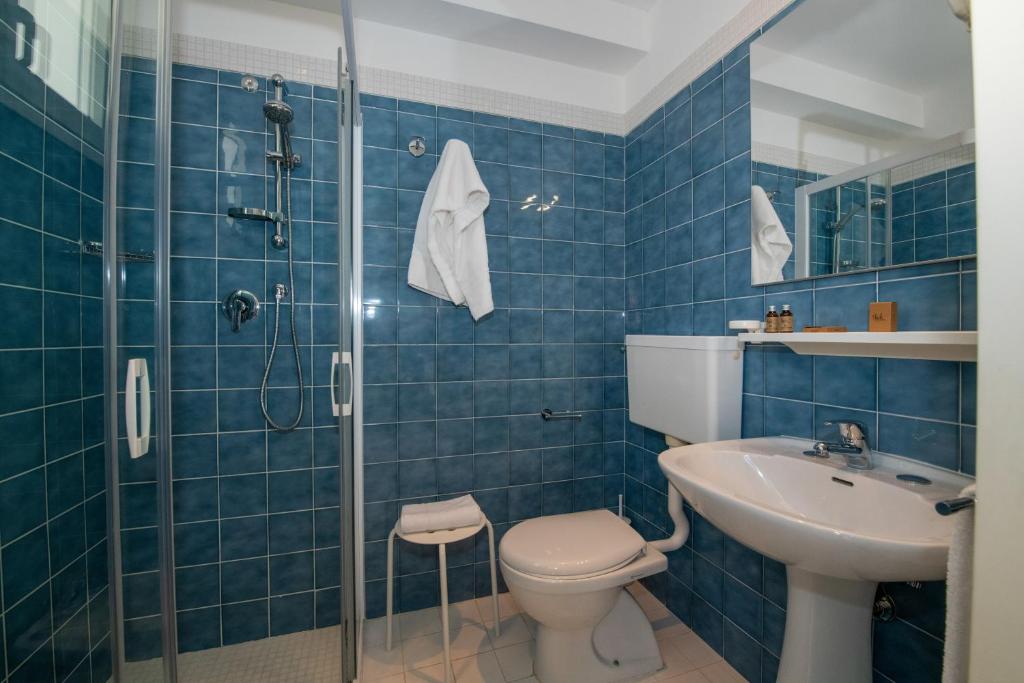 La salle de bains est pourvue de carrelage bleu, de toilettes et d'un lavabo. dans l'établissement Hotel Delle Mimose, à Lido di Jesolo