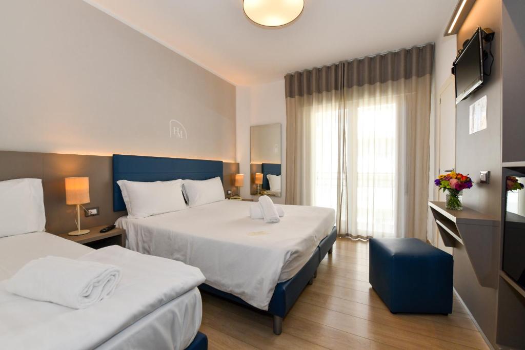 une chambre d'hôtel avec deux lits et une fenêtre dans l'établissement Hotel Delle Mimose, à Lido di Jesolo 43 autres photos