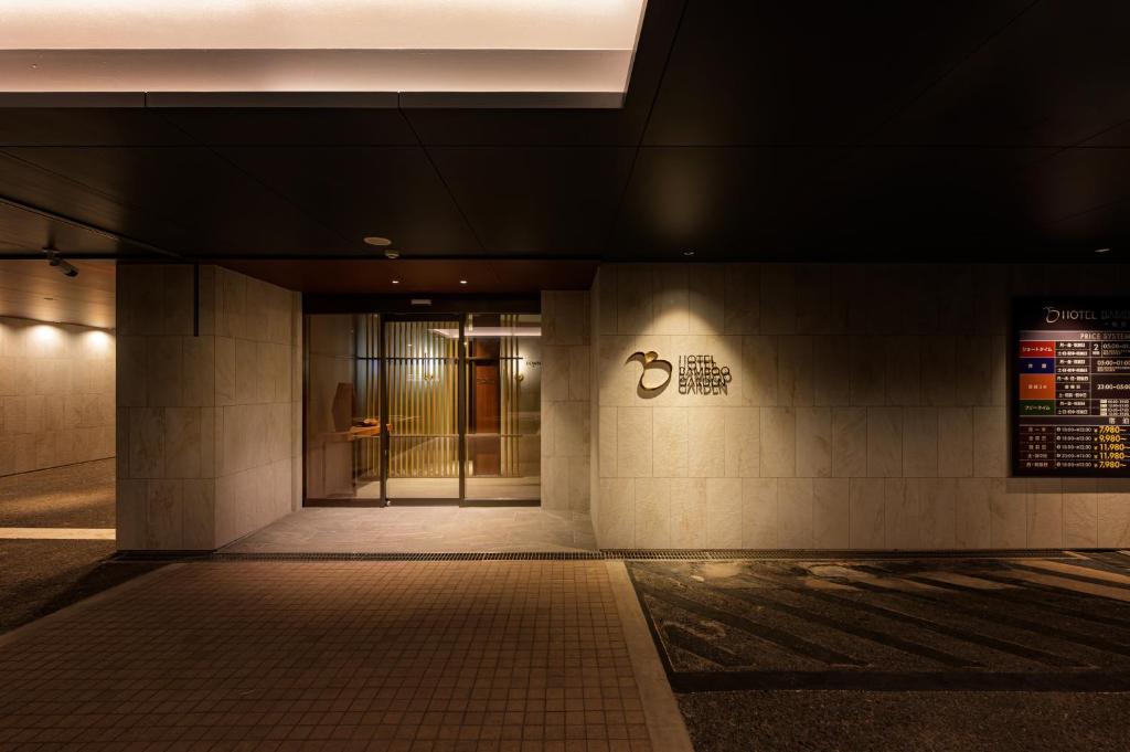 une entrée d'un bâtiment avec un panneau sur le mur dans l'établissement BAMBOO GARDEN 相模原, à Sagamihara