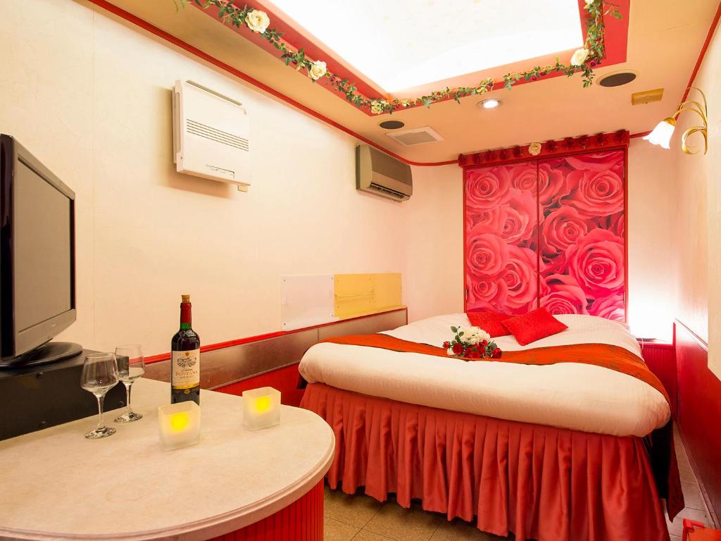 une chambre avec deux lits et une table avec une bouteille de vin dans l'établissement Hotel Gallery (Adult Only), à Kobe