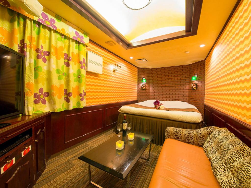 une salle de train avec un lit, un canapé et une table dans l'établissement Hotel Gallery (Adult Only), à Kobe