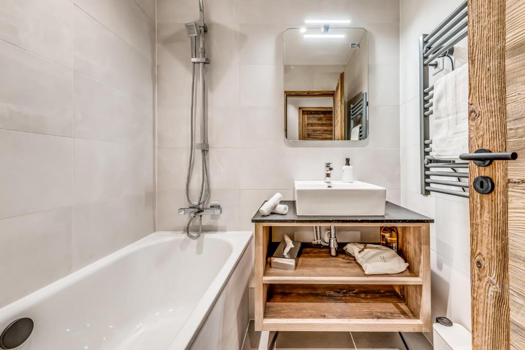 une salle de bain avec une baignoire blanche et un lavabo dans l'établissement Arc 1950 - Charmant Appart 2-4 pers dans résidence hôtelière, Skis aux pieds, à Arc 1950