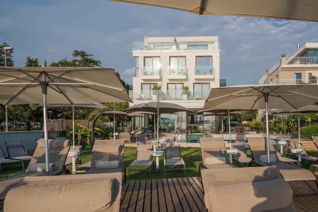 un groupe de chaises et de parasols devant un bâtiment dans l'établissement Hotel Vinci, à Sirmione