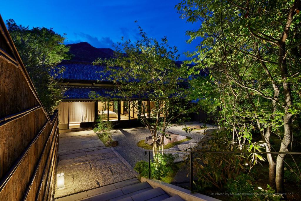 un jardin avec une clôture en bois et des arbres la nuit dans l'établissement LOQUAT西伊豆, à Izu