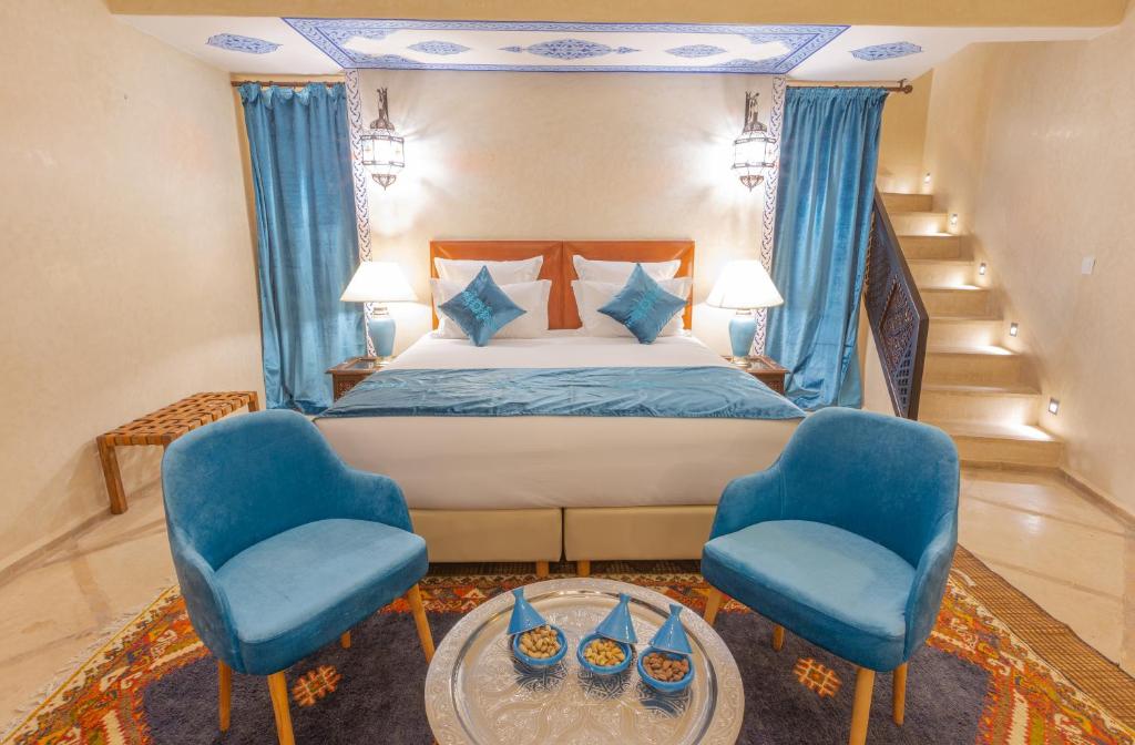 - une chambre avec un lit et deux chaises bleues dans l'établissement Riad El Hara, à Marrakech