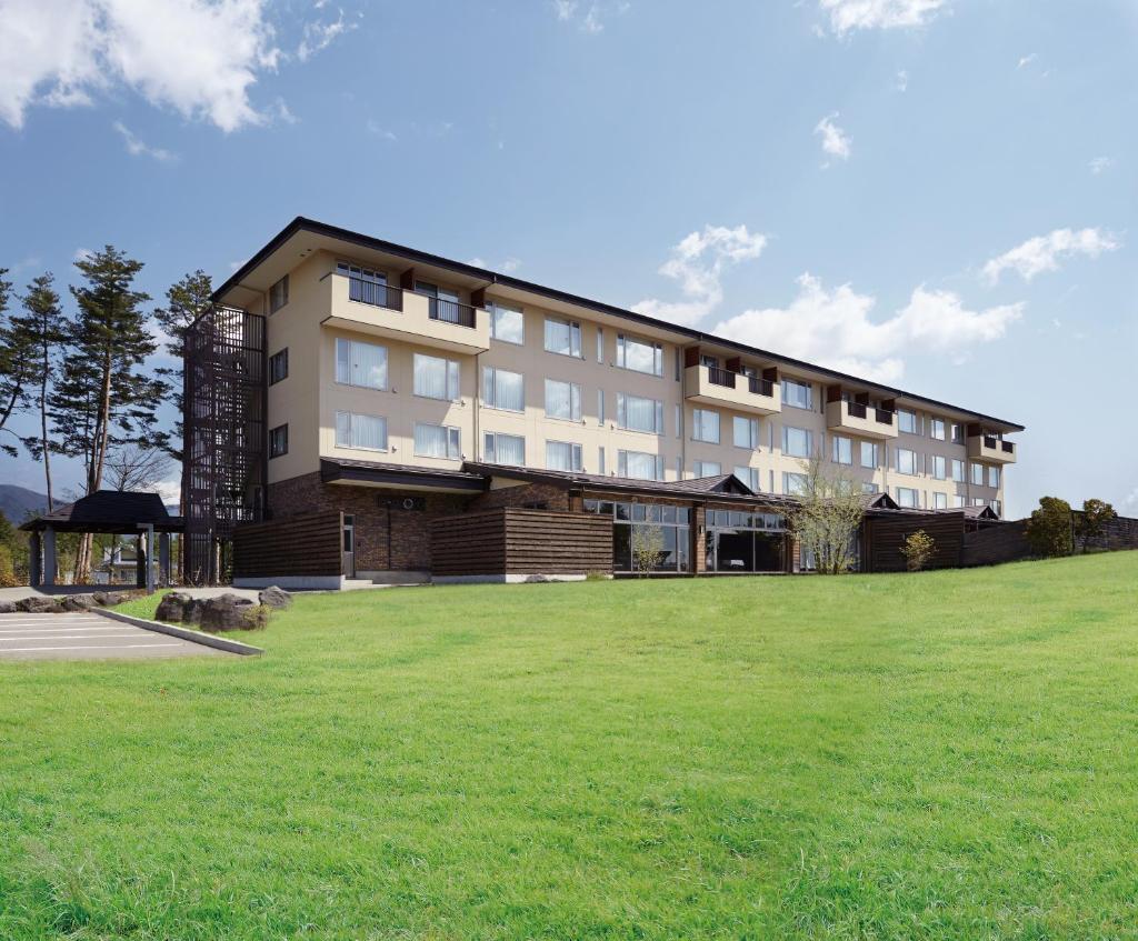 un grand bâtiment au-dessus d'un champ verdoyant dans l'établissement The Gran Resort Princess Fujikawaguchiko, à Fujikawaguchiko
