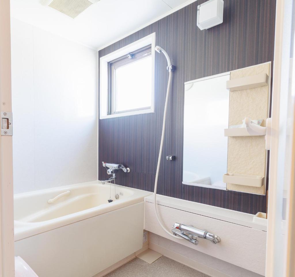 une salle de bain avec une baignoire, un lavabo et un miroir dans l'établissement Hotel Wave大人専用, à Hiroshima
