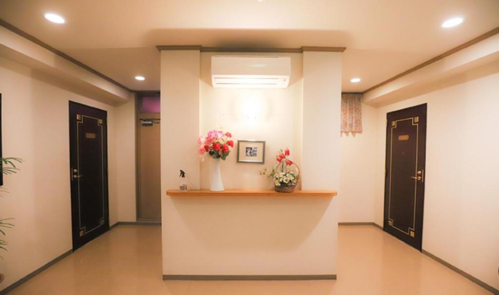 - un couloir avec deux portes et des fleurs sur une étagère dans l'établissement Hotel Wave大人専用, à Hiroshima