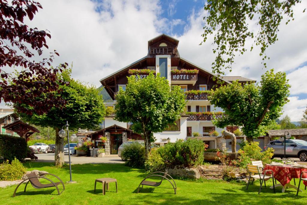 un hôtel avec une cour herbeuse en face d'un bâtiment dans l'établissement Hôtel Le Sporting, à Morzine