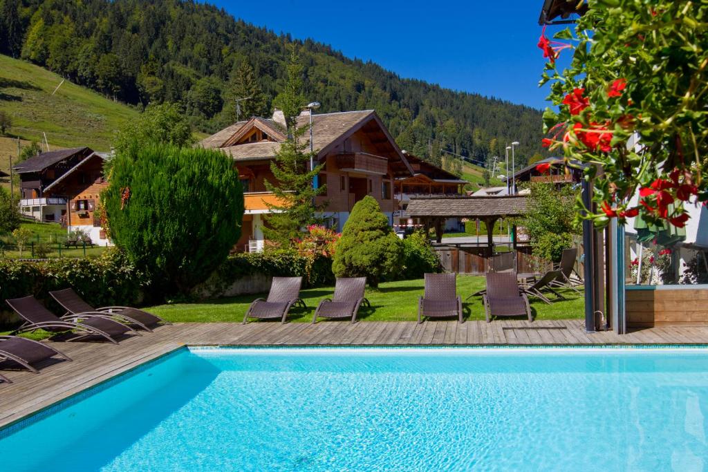 une piscine avec des chaises et une maison dans l'établissement Hôtel Le Sporting, à Morzine
