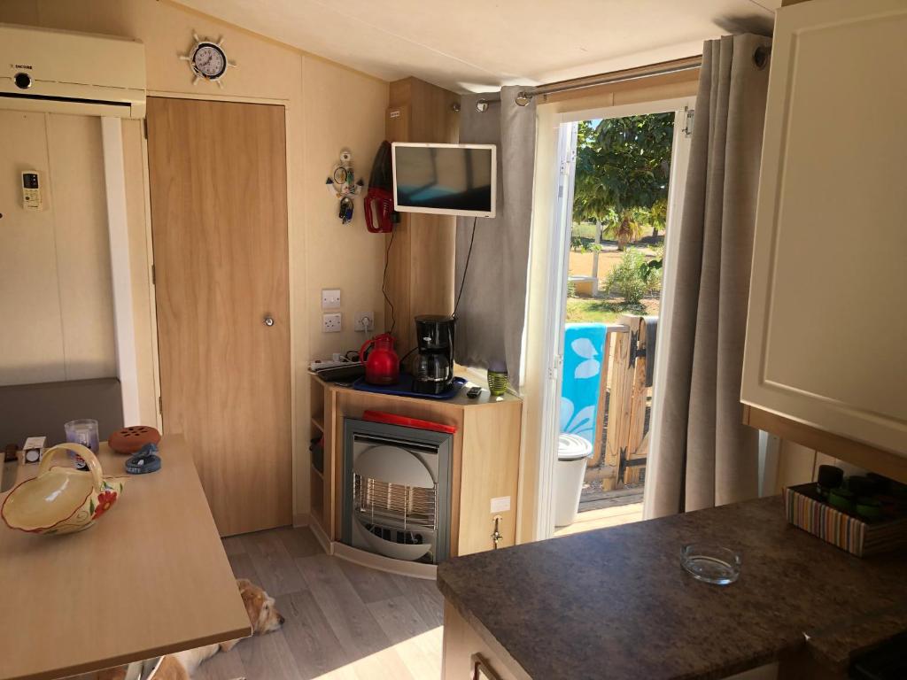 Elle comprend une petite cuisine avec une cheminée et une porte donnant sur une cour. dans l'établissement Cathy & David-Mobile Home 11-Camping Novela, à Port-la-Nouvelle