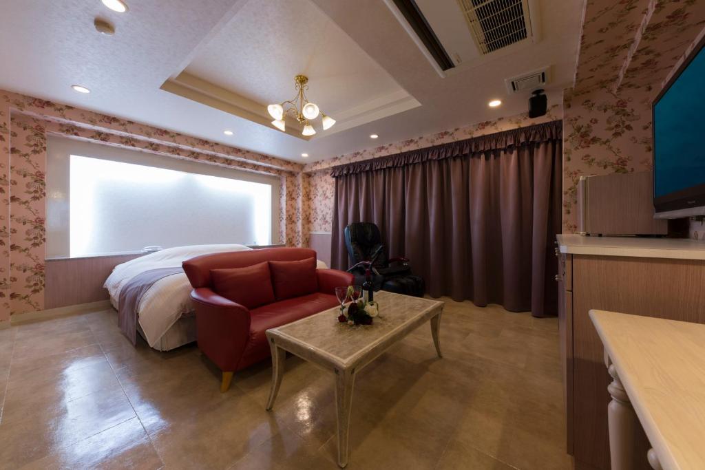 - une chambre avec un lit, une chaise rouge et une table dans l'établissement Hotel Rea Tiare - Adult Only-, à Himeji