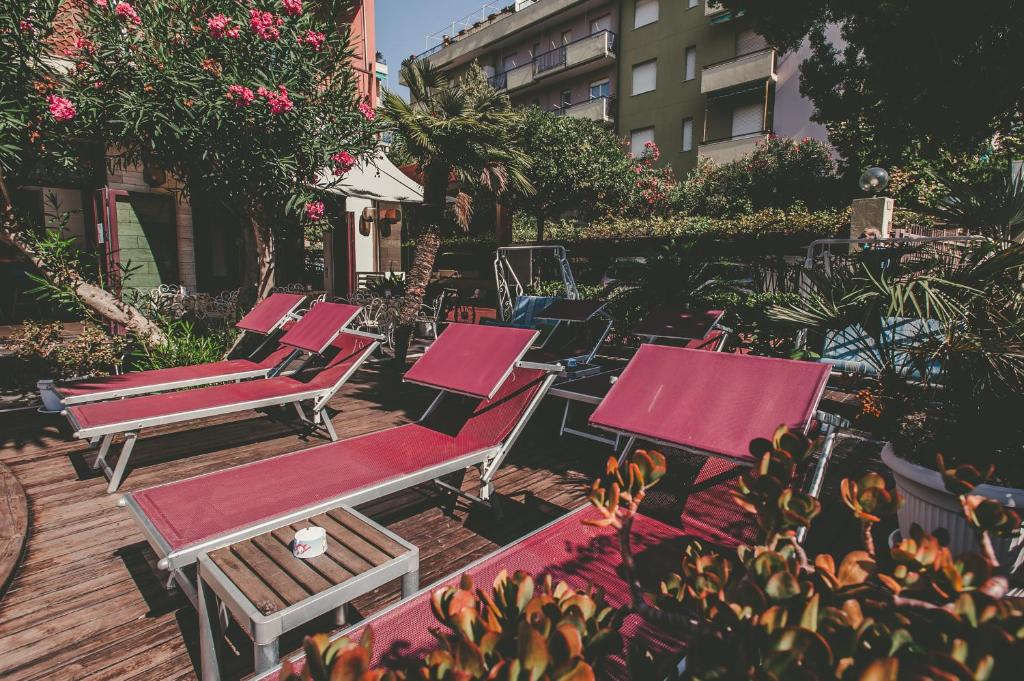 une rangée de chaises rouges assises sur une terrasse en bois dans l'établissement Ligure Residence Appartamenti per Vacanze, à Pietra Ligure