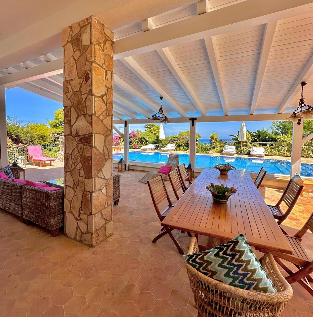 un patio avec une table et des chaises et une piscine dans l'établissement Stunning Seafront Villa in Scopello Pool & Jacuzzi, à Scopello