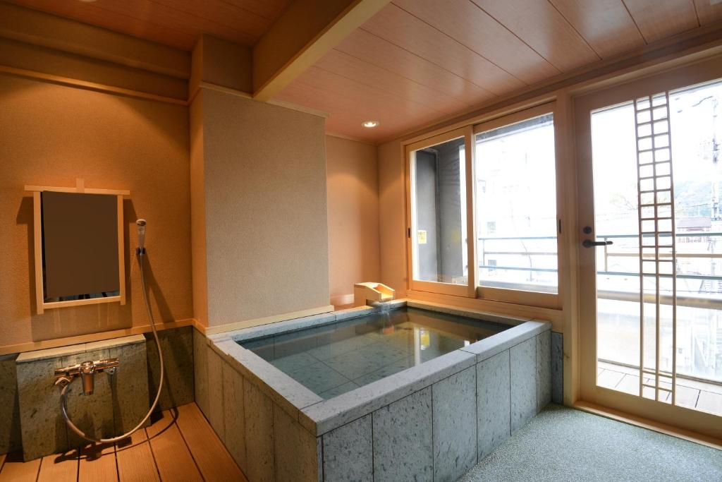 La salle de bains est pourvue d'une grande baignoire et d'une fenêtre. dans l'établissement こんぴら温泉 貸切湯の宿 ことね, à Kotohira 37 autres photos