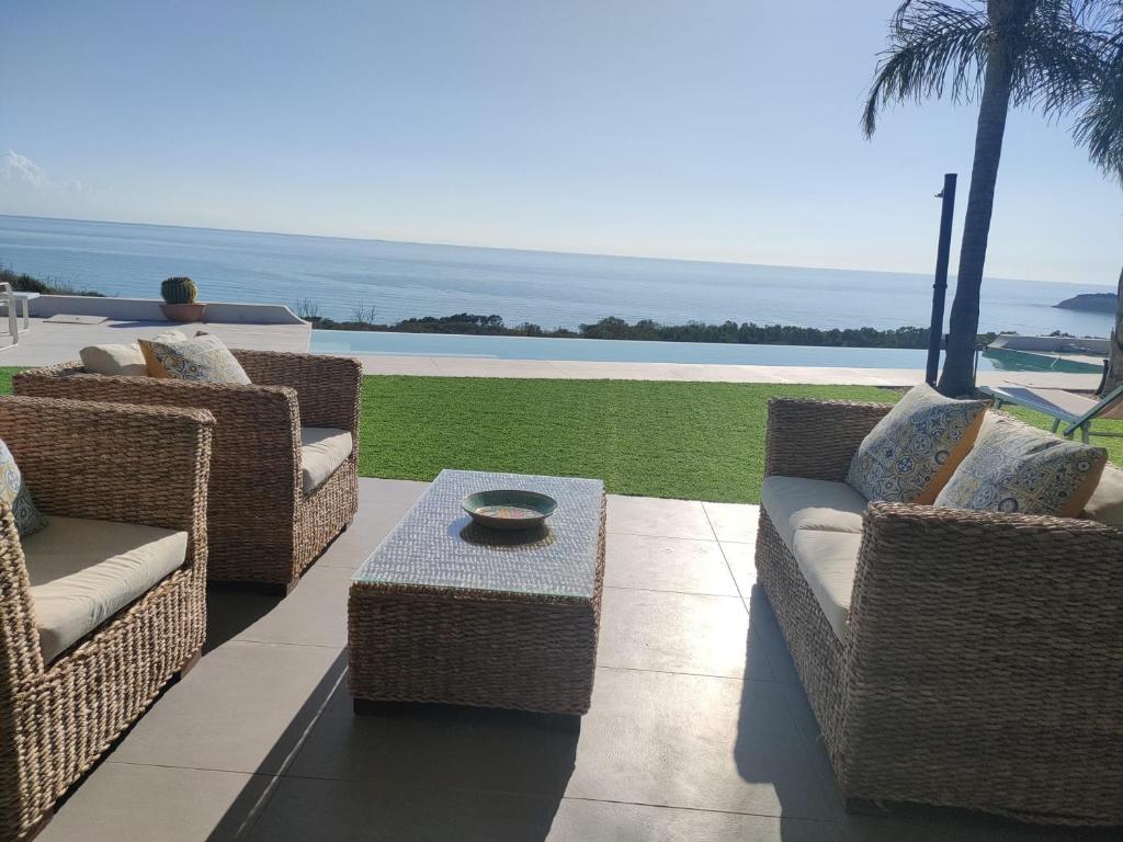 un patio avec des chaises en osier et une table dans l'établissement Villa Gentile, à Eraclea Minoa