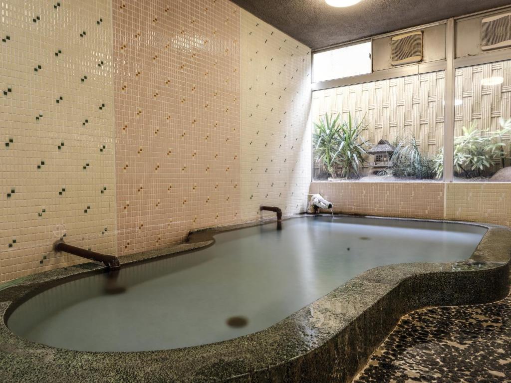 une grande baignoire dans une pièce avec une grande fenêtre dans l'établissement Ohashikan, à Matsue