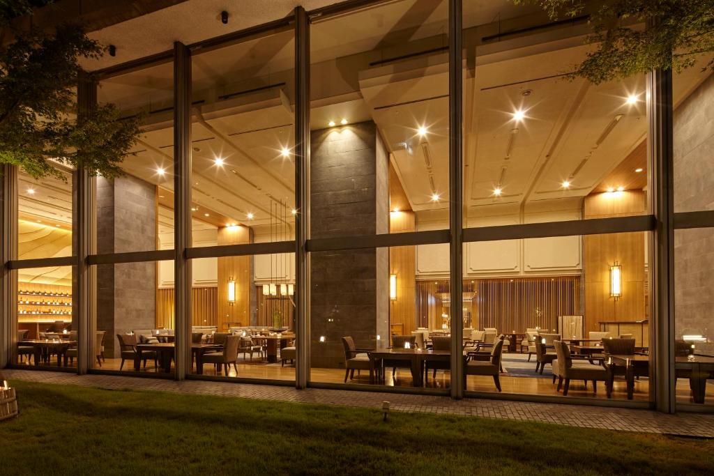 un restaurant avec des tables et des chaises à l'intérieur d'un bâtiment dans l'établissement Takanawa Hanakohro - in Grand Prince Hotel Takanawa, à Tokyo