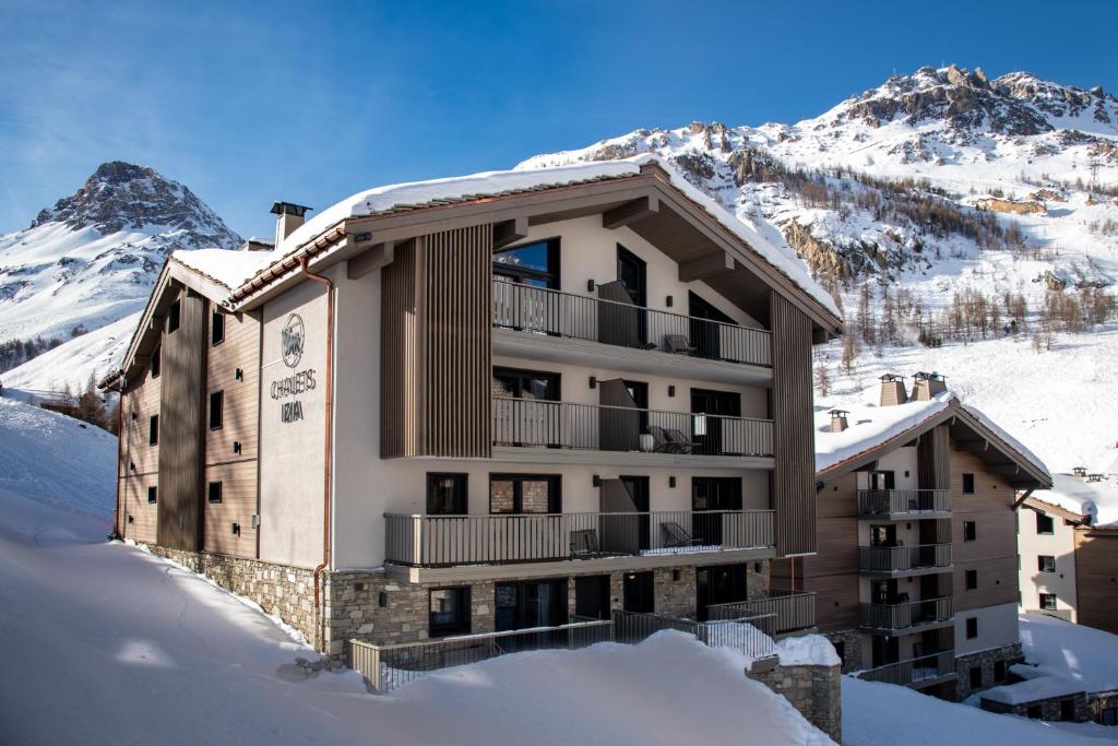 un bâtiment dans la neige avec des montagnes en arrière-plan dans l'établissement Chalets Izia - Village Montana, à Val dʼIsère