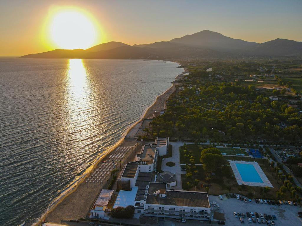 une vue aérienne d'une plage avec le soleil couchant sur l'eau dans l'établissement Eleamare Resort, à Castellammare di Velia