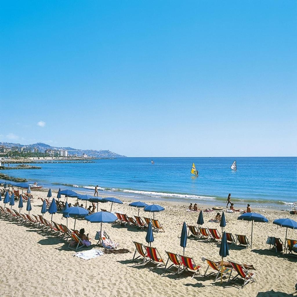 - une plage avec des chaises longues, des parasols et des personnes sur la plage dans l'établissement Hotel Paradiso, à Sanremo