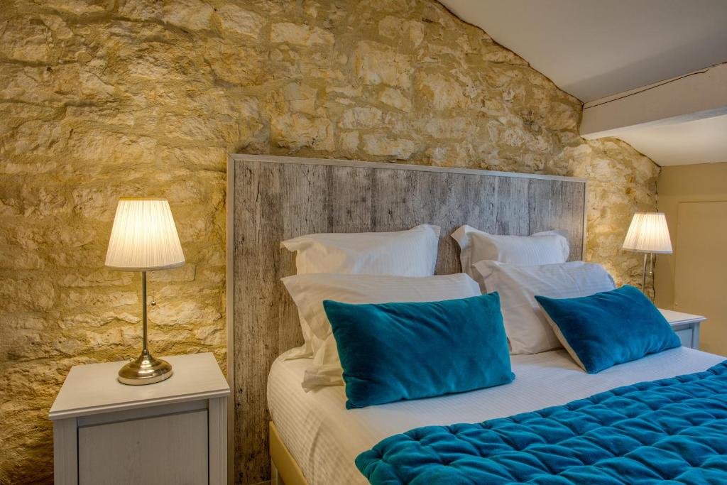 une chambre avec un grand lit avec des oreillers bleus dans l'établissement Domaine des Pierres Blanches - Gite La Salamandre, à Carlux 7 autres photos
