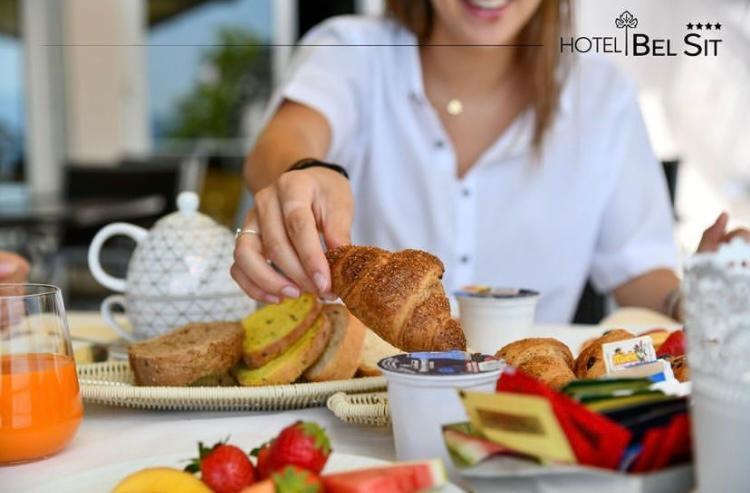 une femme assise à une table avec une assiette de nourriture dans l'établissement Hotel Bel Sit, à Meina